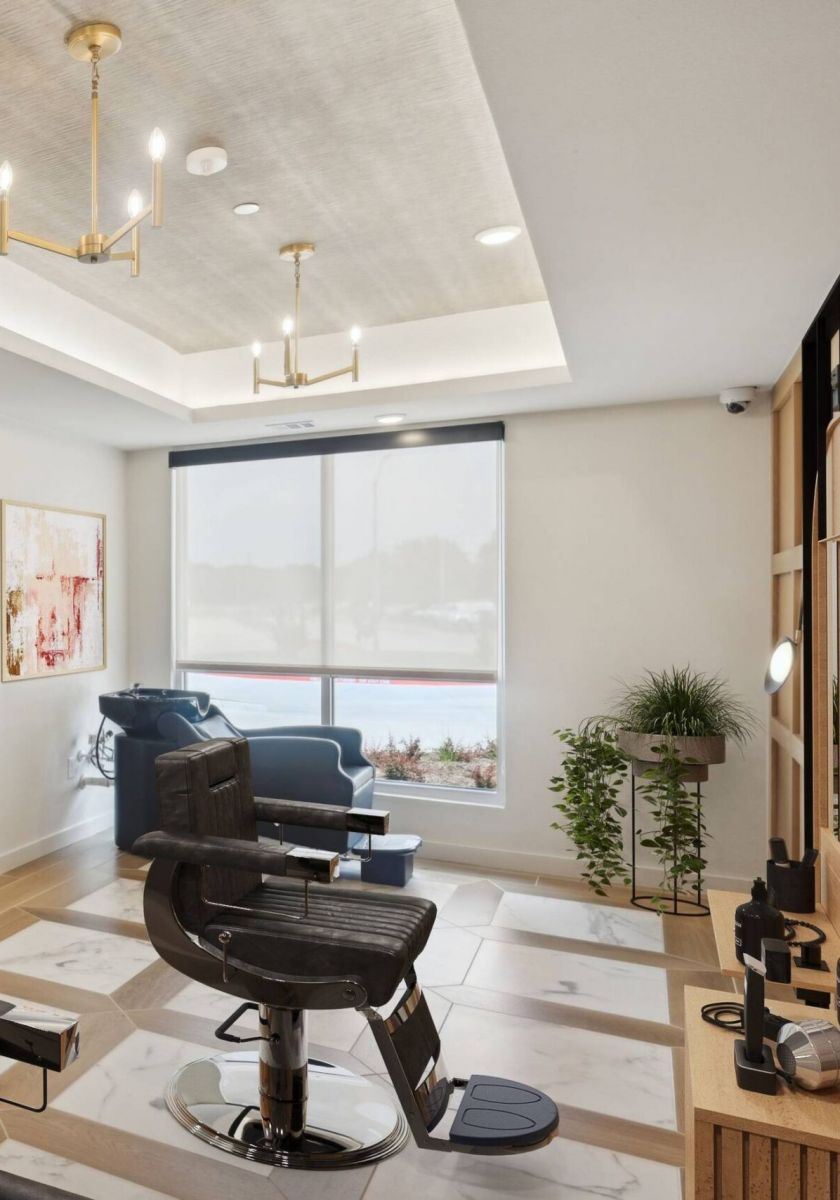 Meridian at Wylie Modern barbershop with wooden cabinets, two black chairs, a large window, and indoor plants.