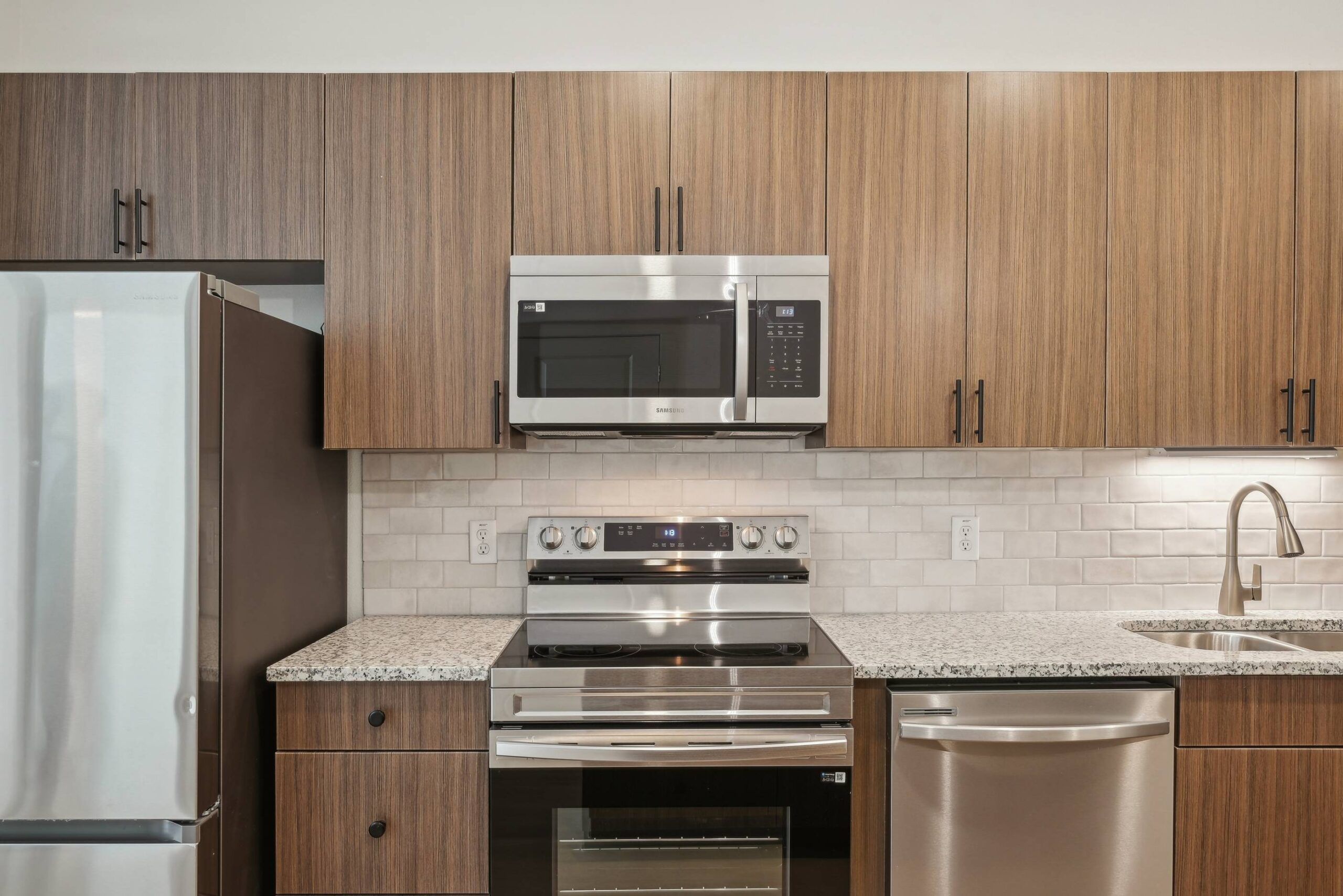 Meridian at Wylie Modern kitchen with wood cabinets, stainless steel appliances, and a tile backsplash.