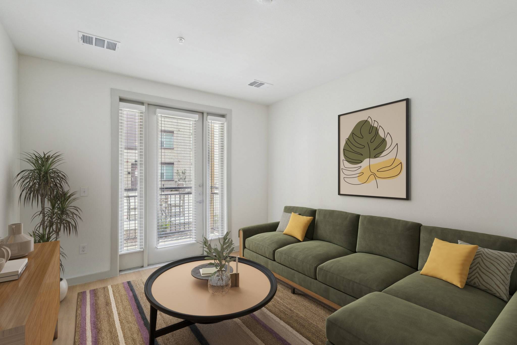 Meridian at Wylie Modern living room with green sofa, round coffee table, large window, and botanical wall art.