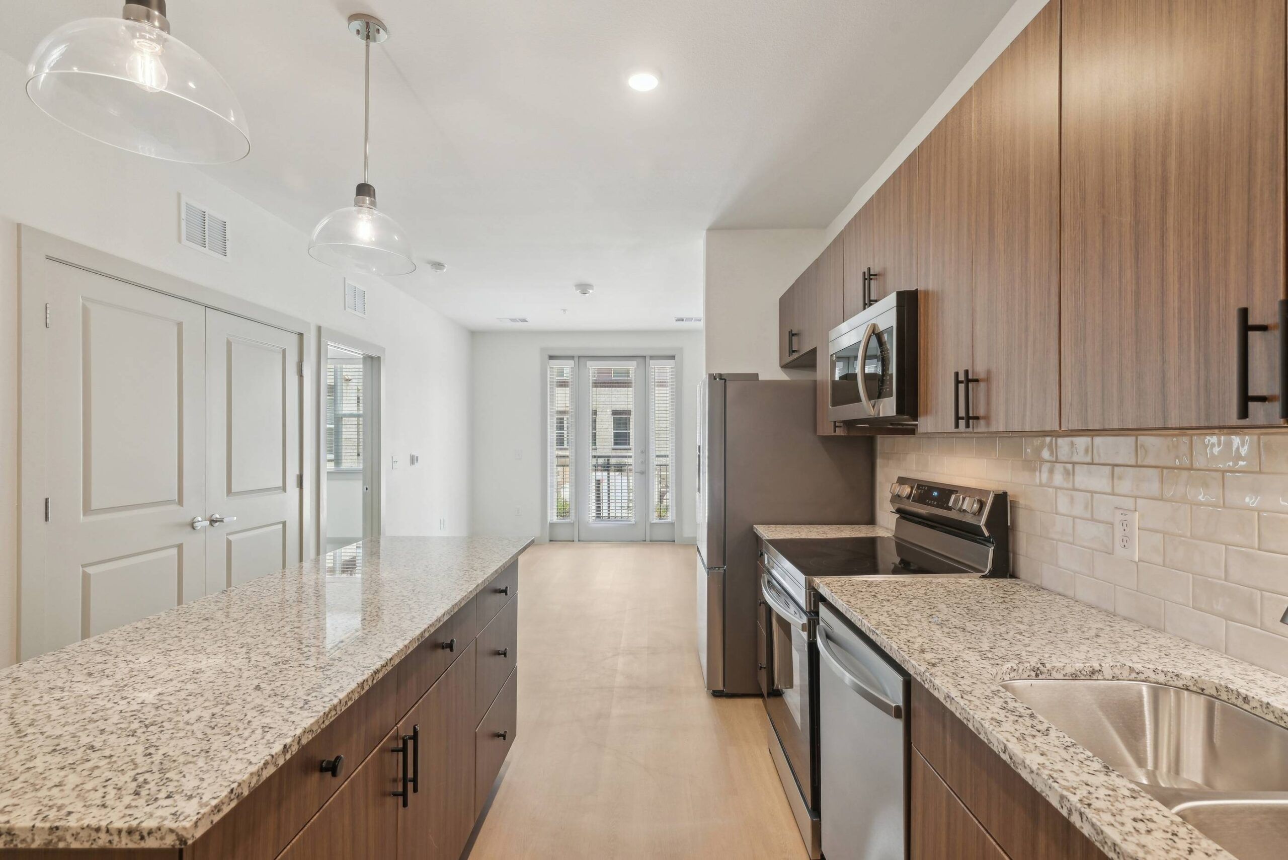 Meridian at Wylie Modern kitchen with wood cabinets, granite countertops, stainless steel appliances, and pendant lighting.