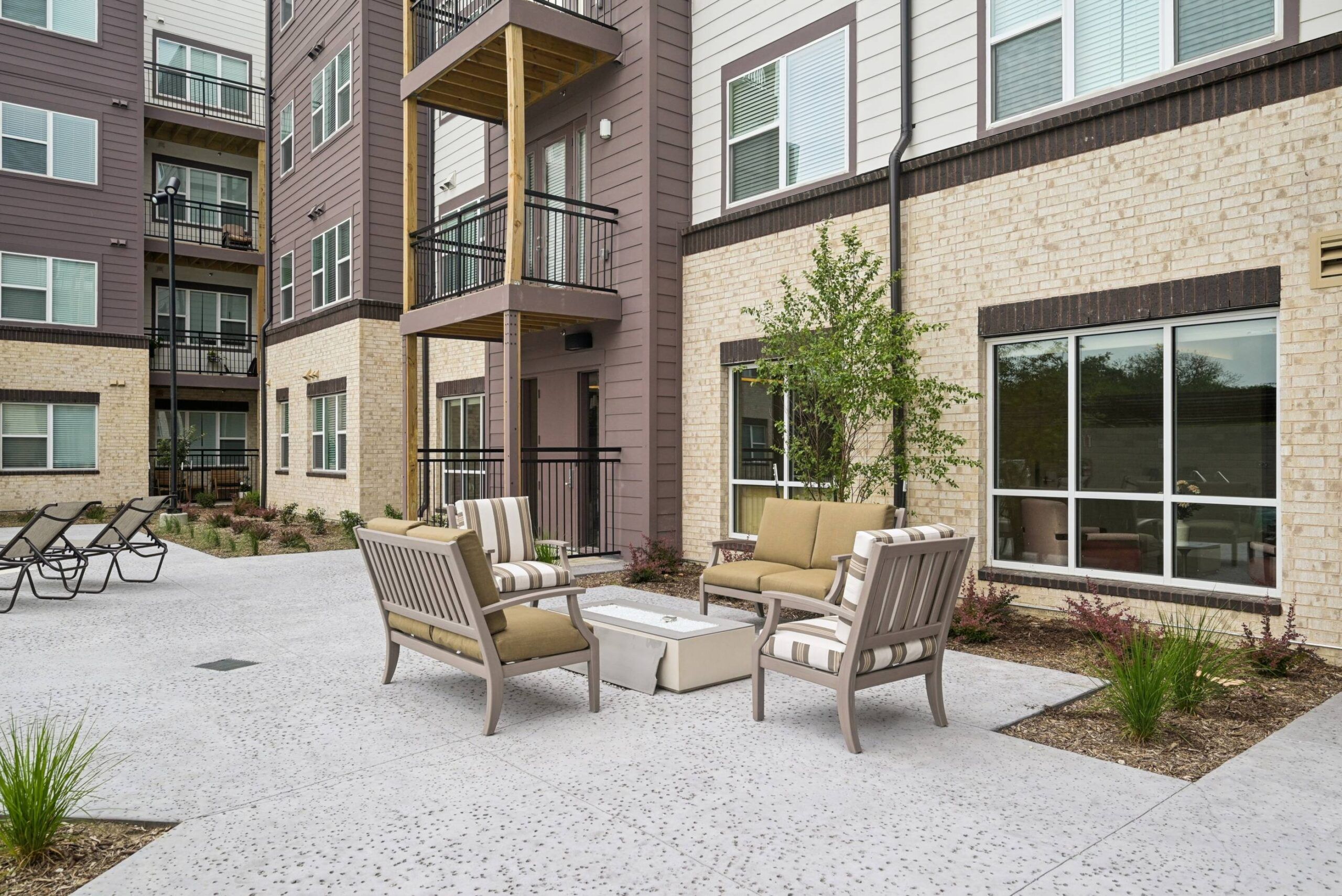 Meridian at Wylie Outdoor patio area with cushioned chairs, a coffee table, and surrounding apartment buildings.