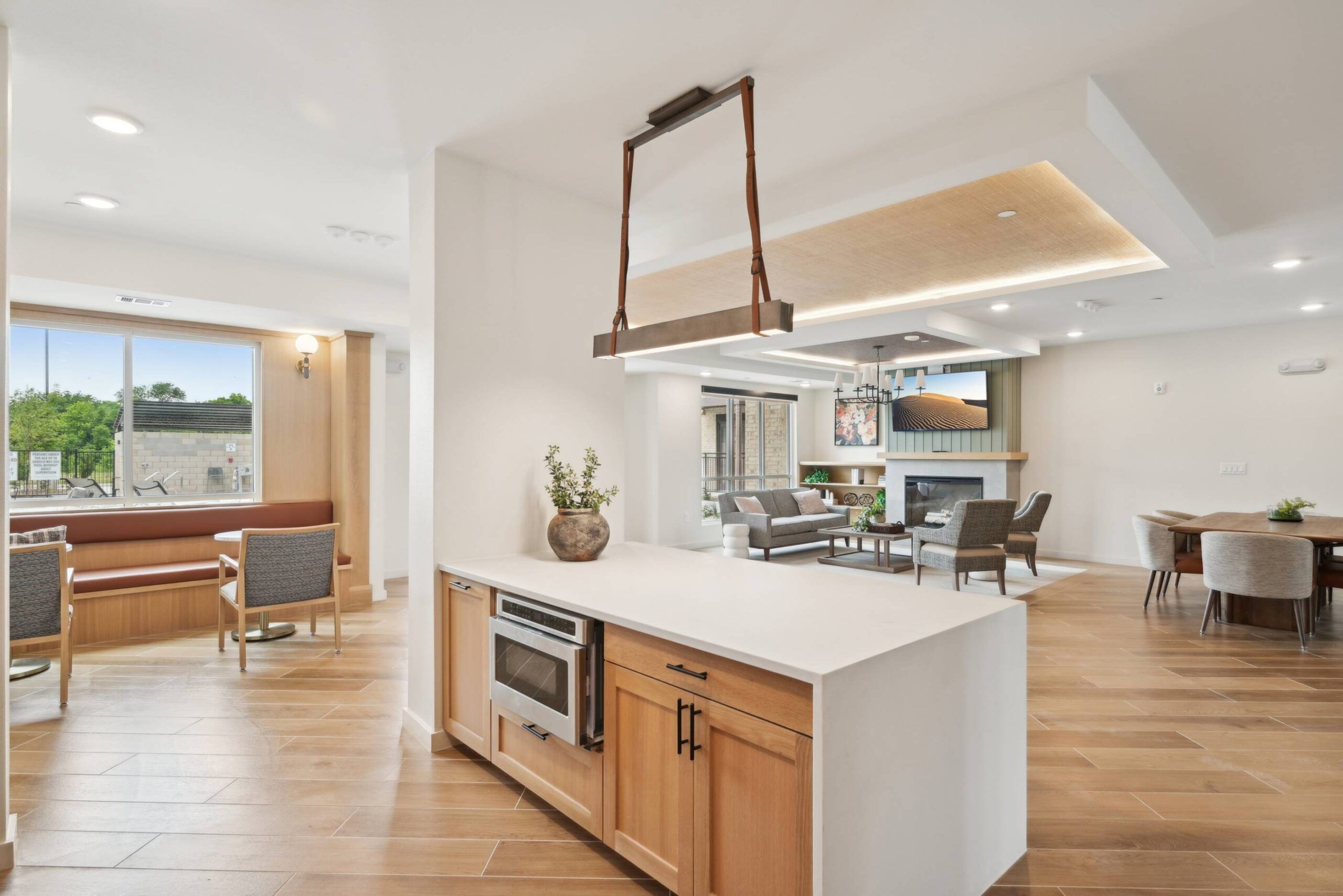 Meridian at Wylie Modern open kitchen and living area with wood flooring, island, dining table, and large windows.
