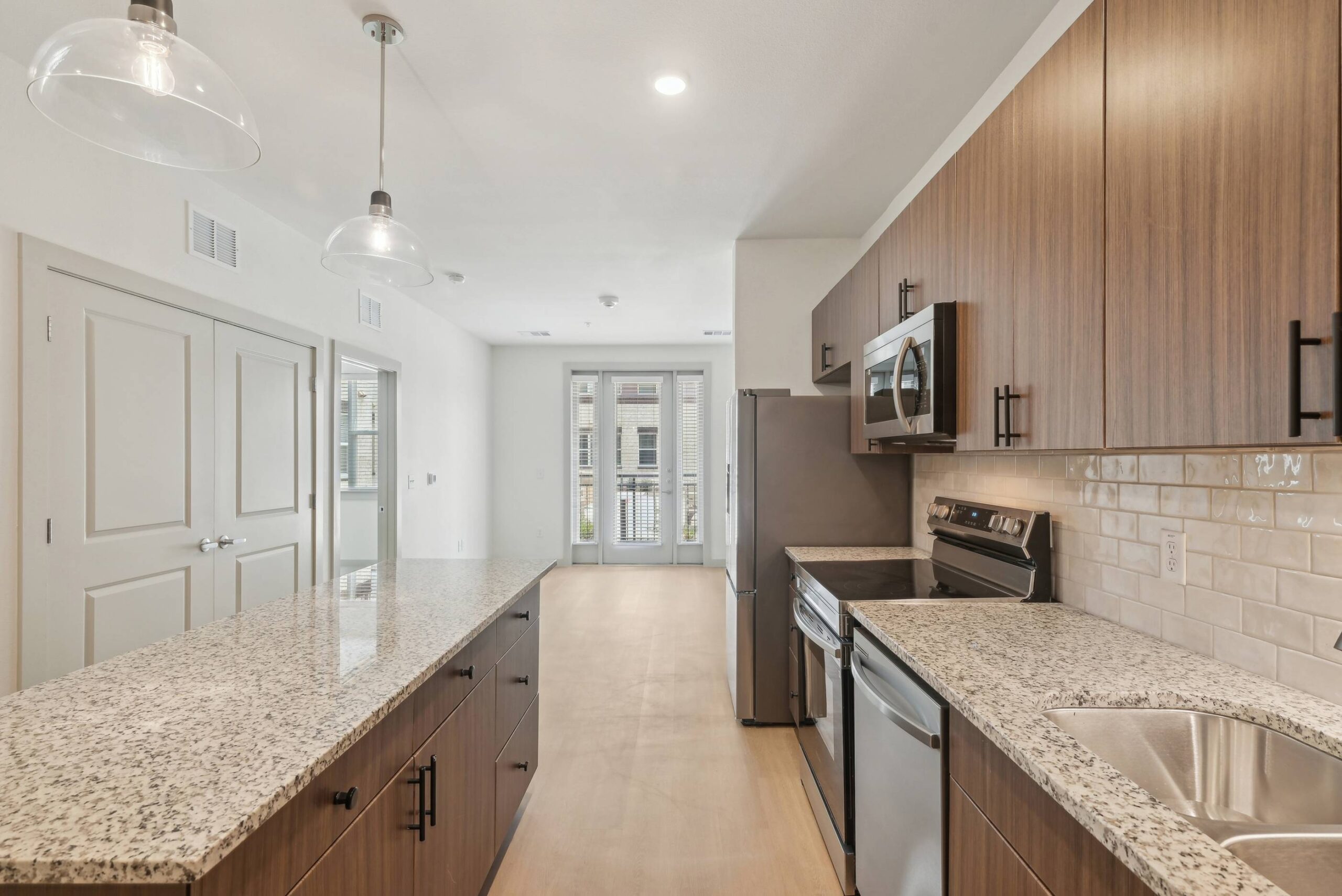 Meridian at Wylie Modern kitchen with wood cabinets, granite countertops, stainless steel appliances, and pendant lighting.